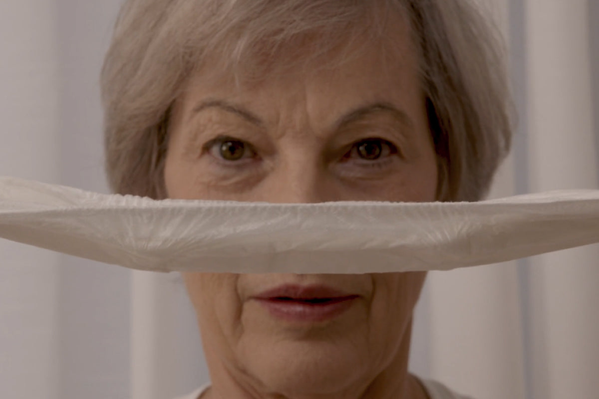 older woman holding an incontinence pad in front of her face