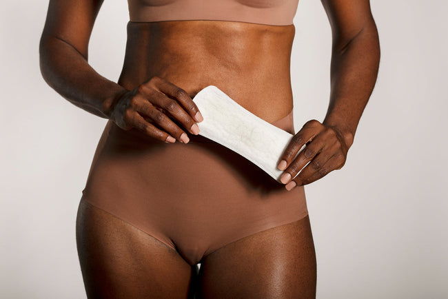 woman holding incontinence liner in front of her body