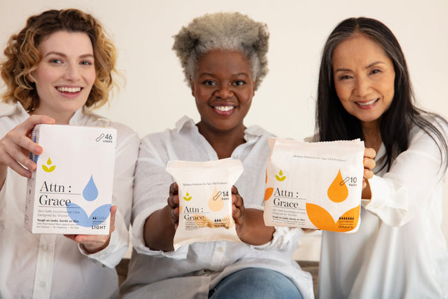 three women sitting together hold Attn: Grace pads