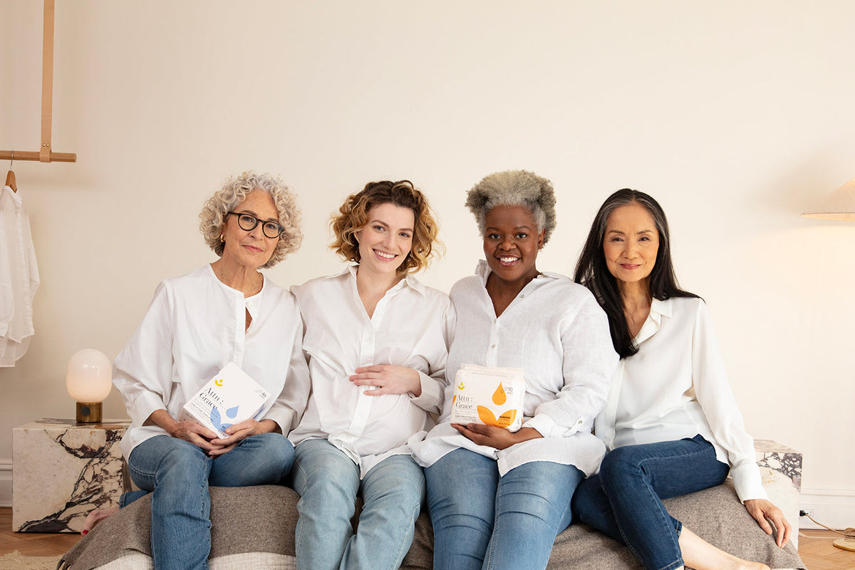 Women sitting next to each other on a bed holding Attn: Grace bladder lea pads