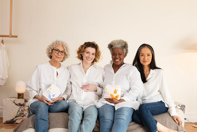 Women sitting next to each other on a bed holding Attn: Grace bladder lea pads