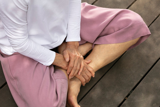 woman sitting cross legged on the ground with her hands in her lap