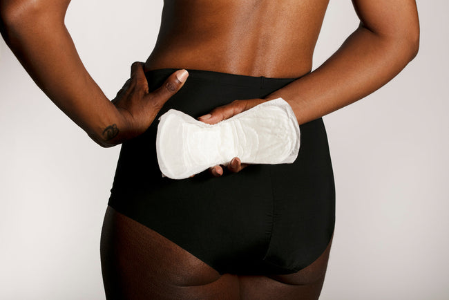 woman holding an Attn: Grace bladder leak pad behind her back