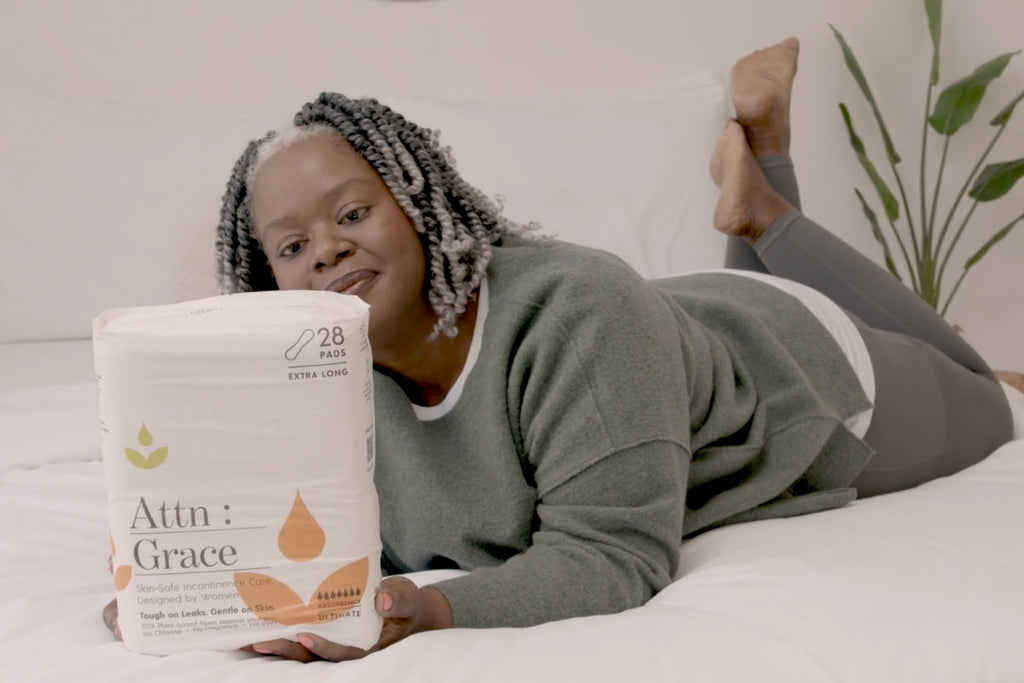 woman laying on a bed holding pack of pads in her hands