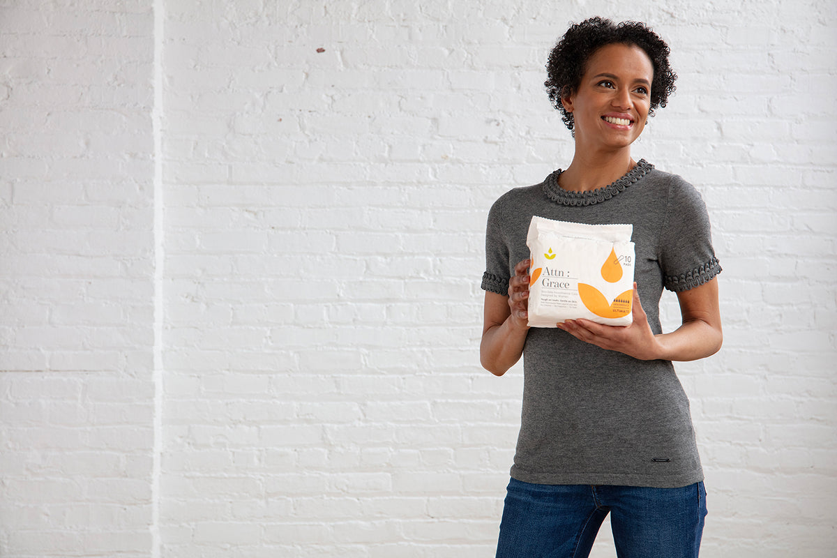 woman holding pack of Attn: Grace incontinence pads