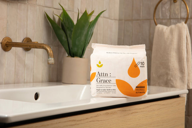 Pack of Attn: Grace incontinence pads on a bathroom sink counter
