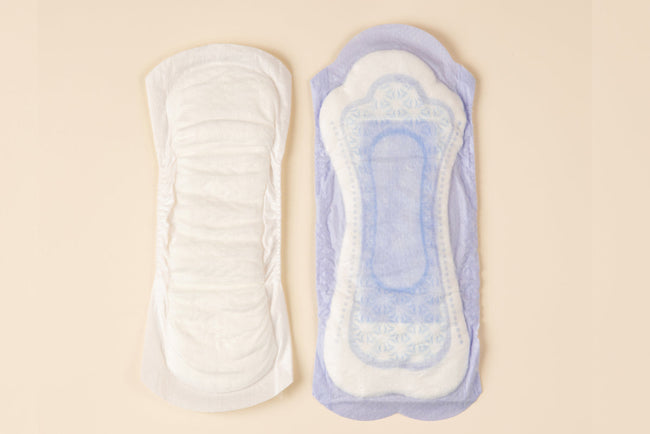 two incontinence pads side by side on a beige background